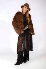 Vestido midi de color negro con acabado brillante, cuello redondo y mangas tres cuartos. Presenta un diseño ajustado en la parte superior con drapeado lateral y una falda inferior confeccionada en encaje transparente.