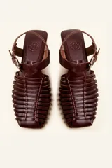 Sandalias planas tipo huarache de cuero negro, con tiras entrelazadas a mano y tira ajustable en el talón con hebilla metálica.