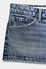 Shorts de jean de tiro bajo con diseño de cinco bolsillos, cierre frontal con cremallera y botón metálico.