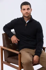 Buzo tejido de punto fino en algodón, con cuello alto y medio cierre frontal con detalle en cuero. Presenta puños y ruedo acanalados.