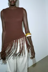 Top de cuello redondo y manga sisa, color marrón, con bajo asimétrico de flecos combinados a tono.