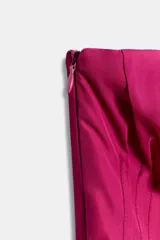 Vestido corto fucsia con escote palabra de honor, cuerpo fruncido, diseño con peplum en la cintura y falda asimétrica con frunces laterales.