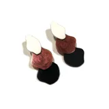 Aros colgantes con tres piezas de formas orgánicas en color blanco, cobre brillante y negro.