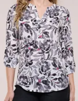 Blusa de gasa estampada de la marca Zac & Rachel, con diseño floral en tonos azul, celeste y verde sobre base blanca. Presenta escote en V con abertura y botones frontales, y mangas largas de largo regulable con presilla.