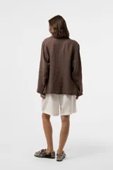 Chaqueta de lino verde militar de calce relajado, con solapa clásica, cierre frontal con dos botones grandes y bolsillos delanteros con solapa.
