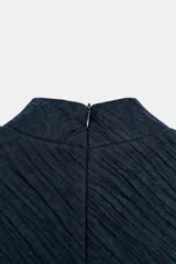 Top corto azul marino de cuello subido y manga corta, confeccionado en tejido con efecto arrugado y detalle de encaje blanco en el ruedo. Cuenta con forro interior y cierre en la espalda con cremallera oculta.
