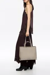 Bolso shopper grande de nylon color marrón, con estructura blanda, doble asa de mano y logo metálico de la marca en la parte inferior frontal. Cuenta con cierre de mosquetón y bolsillo interior.