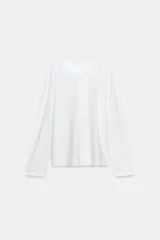 Camiseta blanca de manga larga y corte regular fit, confeccionada en mezcla de algodón y lino. Presenta cuello panadero con cierre frontal de botones y bajo recto.