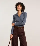 Blusa de manga larga confeccionada en tejido rib acanalado, con cuello polo y escote en V. Presenta un diseño ajustado al cuerpo.