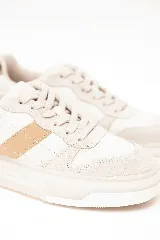 Championes de diseño moderno en tonos beige y blanco, con franja lateral de color tostado y detalle de estampado animal print en el talón. Tienen suela tipo plataforma y cierre con cordones.