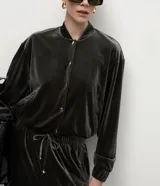 Campera bomber de terciopelo color verde oscuro, con cuello redondo, cierre frontal con botones metálicos, bolsillos laterales y mangas largas con puños elásticos.