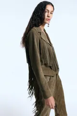 Campera de gamuza color verde militar, de corte entallado, con cierre frontal y diseño de flecos largos en el delantero y la espalda. Presenta un canesú de inspiración western en la parte posterior.
