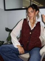 Chaleco tejido color tostado con destellos de lurex, escote en V y cierre frontal con botones. Presenta detalles de bordados y terminaciones en crochet en color crudo.