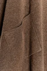 Capa de punto color marrón, con escote en V, mangas cortas y bolsillos de plastrón en el delantero. El ruedo tiene un corte asimétrico.