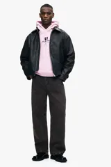 Canguro de algodón con capucha y cordones ajustables, diseño de hombros caídos y bolsillo frontal tipo canguro. Presenta un estampado gráfico en el pecho y puños acanalados.