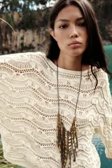 Sweater color crudo de punto calado con cuello barco y manga larga acampanada.