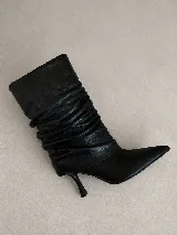 Bota de caña media en cuero negro, con diseño de efecto arrugado en la caña, punta fina y taco fino de altura media.