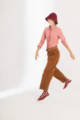 Pantalón de gamuza color marrón, de tiro medio y corte slouchy. Presenta bolsillos laterales y traseros, cierre metálico frontal y forro interno con stretch.