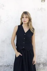 Chaleco negro de pana fina, con escote en V y cierre frontal de botones. Presenta un diseño entallado con corte en la cintura.