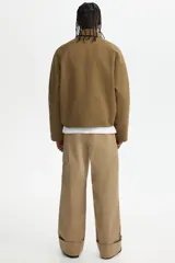 Campera de sarga levemente acolchada con cuello inglés, cierre frontal y solapa con botones. Presenta mangas raglán, bolsillos insertados delanteros y cordón ajustable en el bajo.