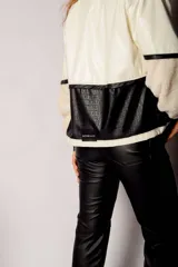 Campera corta de cuero sintético color crema y negro, con cuello, puños y ruedo de corderito.