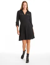 Vestido de crepe color marrón, con cuello solapa, escote en V y cintura elastizada. Presenta bolsillos simulados con cierres metálicos en el frente y mangas largas regulables con presilla y botón.