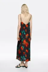 Vestido midi de corte recto con escote en pico, tirantes finos dobles y cierre frontal con botones. Presenta un estampado floral con flores rojas y toques verdes sobre fondo negro.