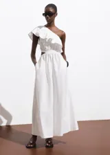 Vestido midi de algodón color blanco con diseño asimétrico de un solo hombro, decorado con un volante. Presenta aberturas laterales tipo cut-out en la cintura y falda con diseño evasé.