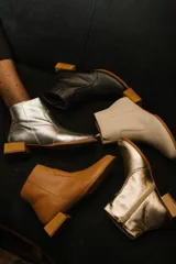 Botín de cuero dorado con punta fina y taco bajo cuadrado de madera.