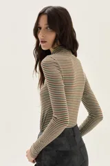 Polera de manga larga con cuello alto, confeccionada en tejido de punto acanalado con diseño de rayas horizontales en color marrón y turquesa. Presenta un bordado pequeño en el pecho y un calce ajustado al cuerpo.