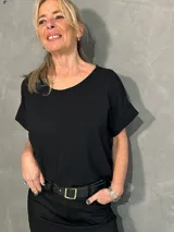 Blusa negra de corte holgado, con cuello redondo y mangas cortas con vuelta.