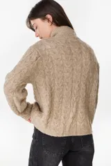 Campera de punto tejido color beige con diseño de ochos, cuello alto y cierre frontal completo.