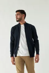 Campera tejida azul marino con cuello alto, cierre frontal y puños acanalados con detalle de línea roja.