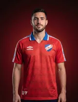 Camiseta de fútbol Umbro del Club Nacional de Football, edición especial EA Sports. Diseño en color rojo con patrón geométrico sutil en zigzag, cuello tipo polo en azul con detalles tricolores, y bandas laterales en las mangas con el logo de Umbro. Incluye el escudo del club y el logo de la marca en el frente.