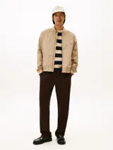 Campera estilo bomber Tommy Hilfiger color beige, con cierre frontal de cremallera, bolsillos laterales de ojal, puños y dobladillo de canalé. Cuenta con el logotipo de la marca bordado en el pecho y un parche distintivo en la manga.