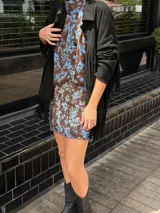 Blusa de seda con estampado floral en tonos marrón y celeste, con cuello alto, manga corta japonesa y cierre cruzado con botones negros visibles en diagonal.