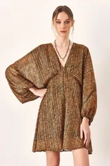 Vestido corto con estampado animal print en tonos marrones y negros, escote en V profundo y mangas largas abullonadas con puño elástico. La cintura está marcada con frunce.