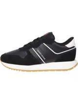 Zapatillas Tommy Jeans negras con detalles en blanco y suela color caramelo. Presentan paneles de cuero y gamuza, cordones negros y logo de la marca en el lateral.