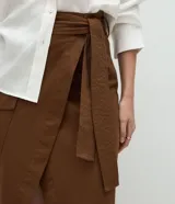 Pollera midi envolvente color marrón, de corte evasé confeccionada en sarga de algodón, con cinturón con lazo en la cintura y diseño cruzado con abertura delantera.