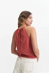 Blusa sin mangas color terracota, con cuello halter fruncido y elástico en la cintura. Presenta un diseño holgado y fresco con acabado tipo lino.