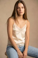 Blusa de satén color champagne con breteles finos, escote en V con detalle de encaje y terminación de encaje en el ruedo.