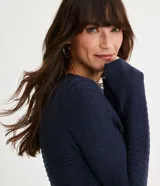 Blusa de punto color celeste con textura ondulada, cuello redondo y mangas largas.