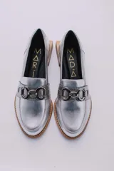 Mocasines de cuero en tono bronce metalizado, con detalle de aplique metálico dorado en el empeine y taco cuadrado bajo de madera.