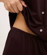 Pijama capri compuesto por una blusa de manga corta con escote en V, detalles de encaje y cierre frontal con botones, y un pantalón capri con cintura elástica y terminaciones en encaje en el bajo.