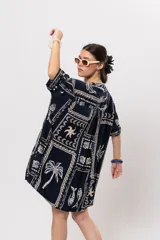 Camisa oversize azul marino con estampado de motivos marinos, palmeras y elementos geométricos en tonos claros. Presenta cuello mao y cierre frontal de botones.