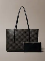 Cartera tote Calvin Klein de diseño estructurado, color negro y marrón con estampado de monograma CK en toda la superficie. Cuenta con asas de mano dobles y finas, y viene acompañada de una mini cartera lisa con cierre y detalle del logo de la marca en dorado.