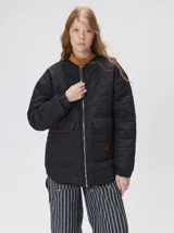 Campera reversible capitoneada con cierre frontal. Un lado es de color negro y el otro es de color beige, ambos con diseño acolchado. Cuenta con cuello redondo, mangas largas y bolsillos laterales.