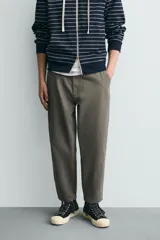 Pantalón de corte carrot fit confeccionado en tejido de algodón con estructura diagonal y efecto lavado. Presenta bolsillos frontales con bolsillo cerillero, bolsillos traseros de plastrón y cierre frontal con cremallera y botón.