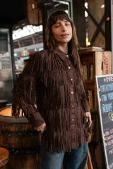 Chaqueta de gamuza marrón con diseño de flecos en la parte delantera y las mangas, corte tipo camisa y cierre frontal de botones.