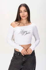 Remera crop blanca de manga larga, con escote asimétrico estilo off-shoulder y estampa frontal con la frase "White Satin" en letra cursiva negra.